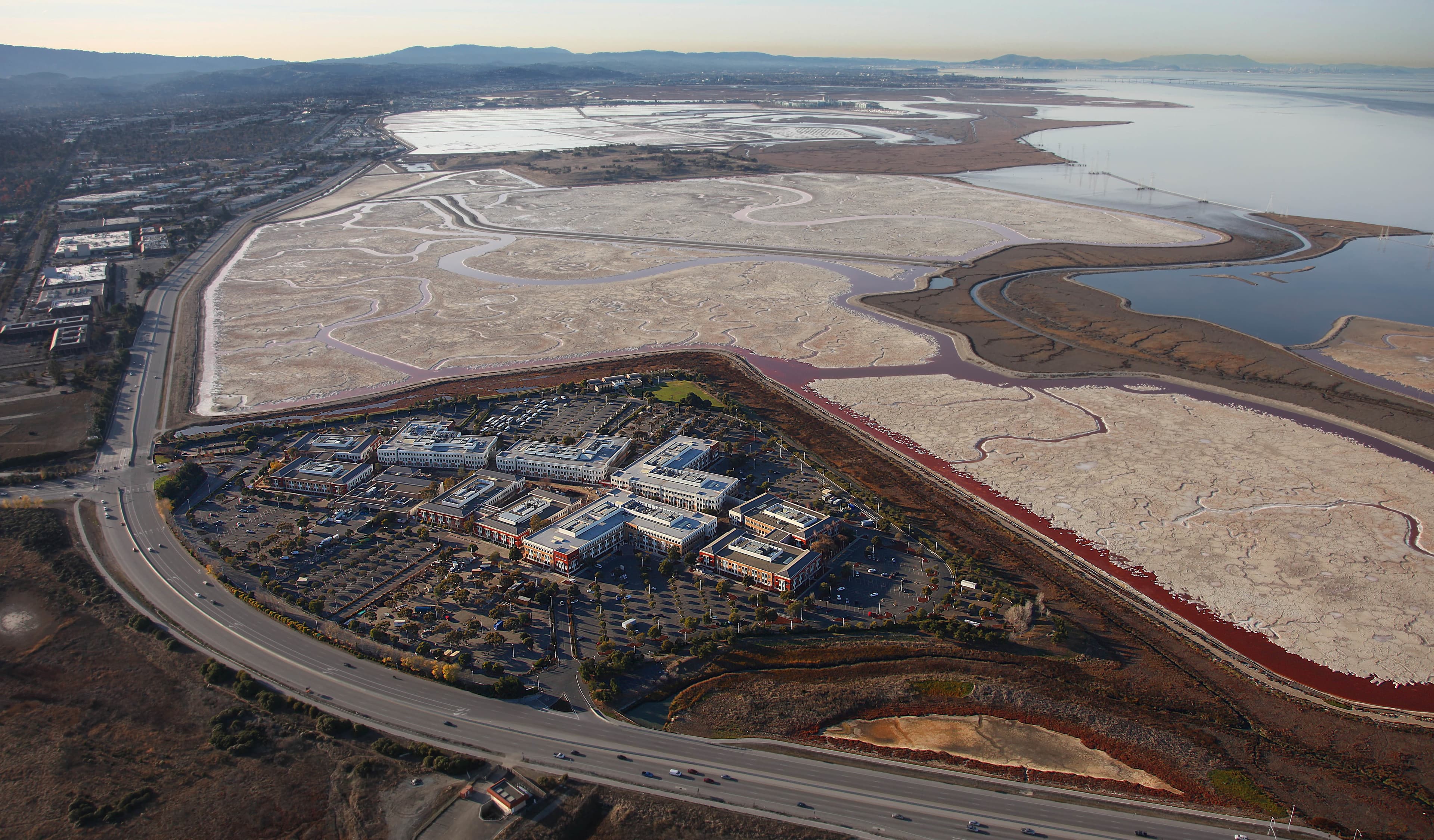 Aerial view of the Facebook Menlo Park campus beside pink salt ponds and San Francisco Bay wetlands