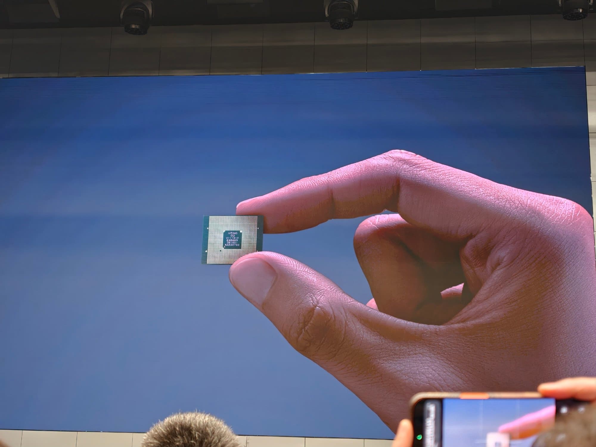 Hand holding a Xiaomi Xring O3 package labeled XRING O3 V1.1.0-C on stage