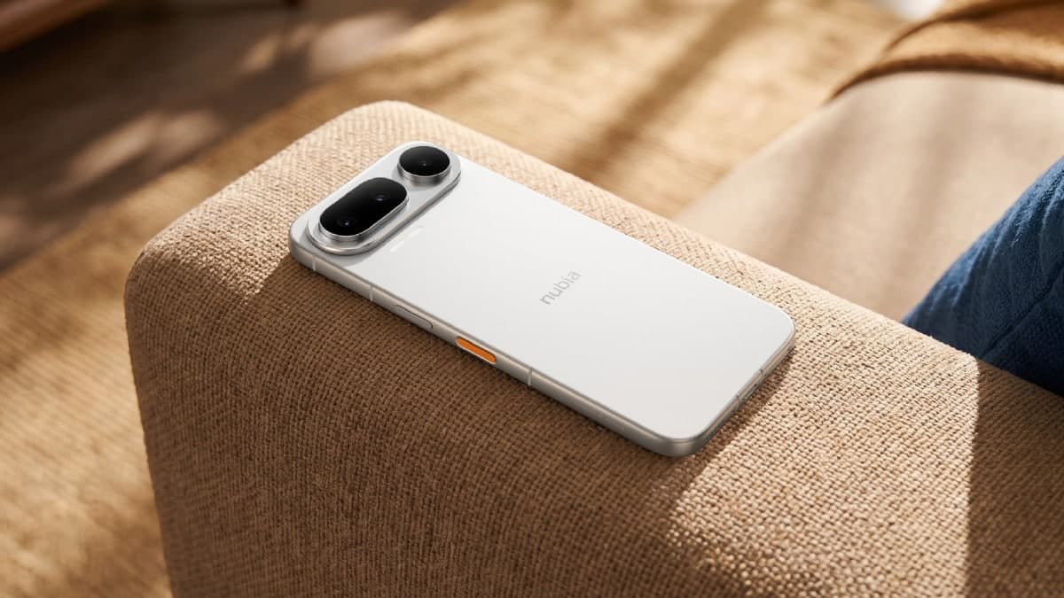 The white nubia NaviX Ultra lying face-down on a sofa arm, showing its horizontal camera island and orange AI key