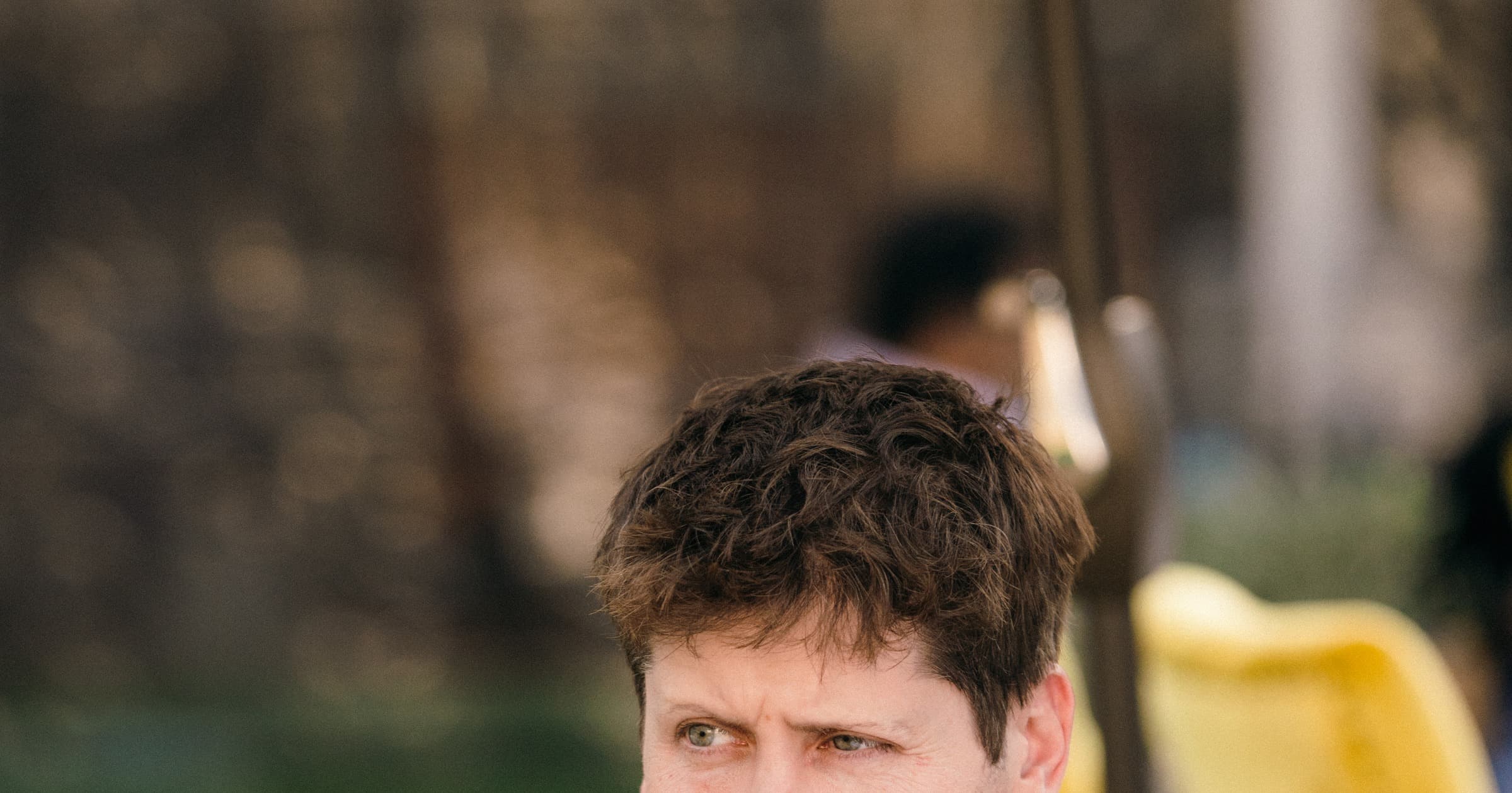 Sam Altman, OpenAI's CEO, seated outdoors in a grey sweater