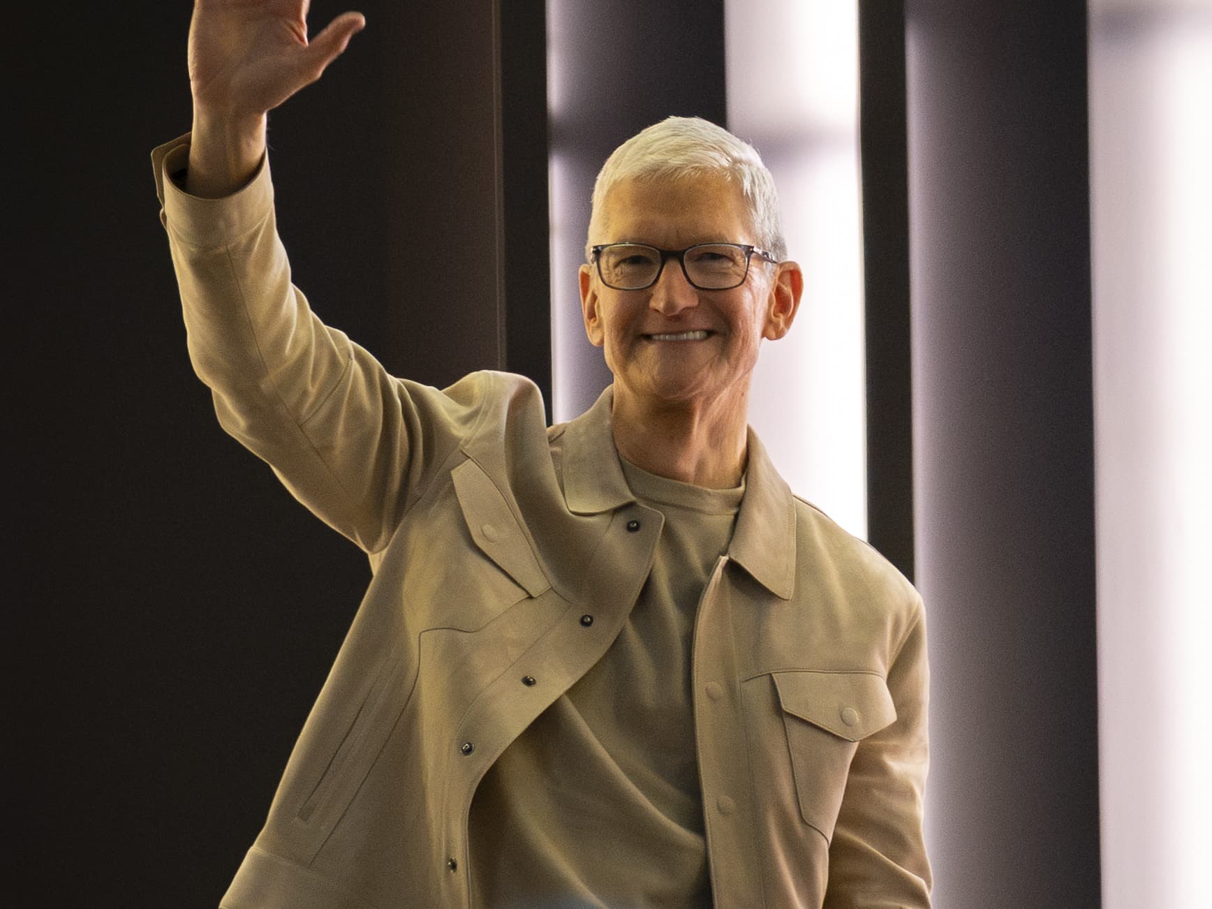 Tim Cook in a beige shirt-jacket waving and smiling at Apple's Grand Central Terminal store event in March 2026